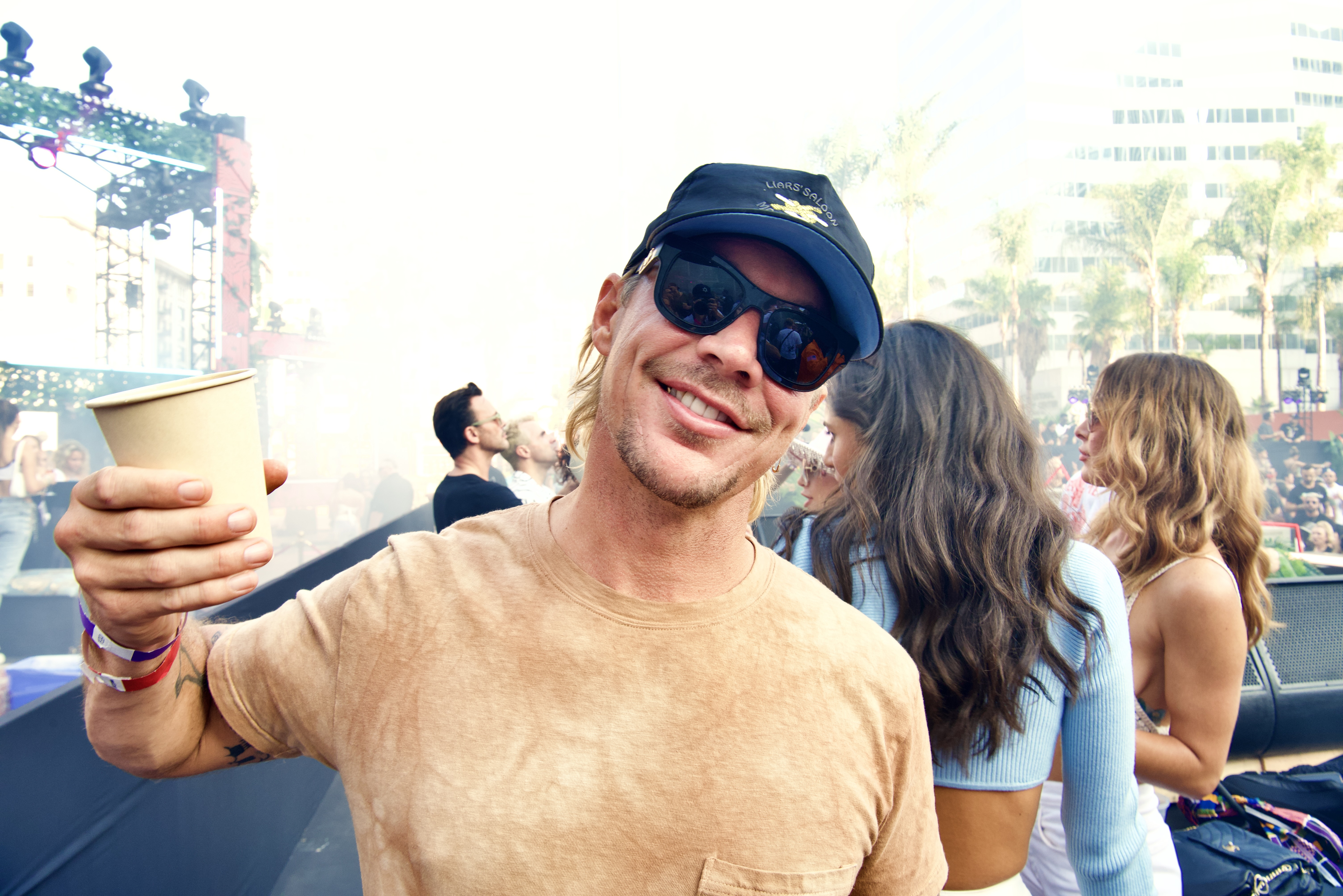 Diplo attends the event, standing with a beverage.