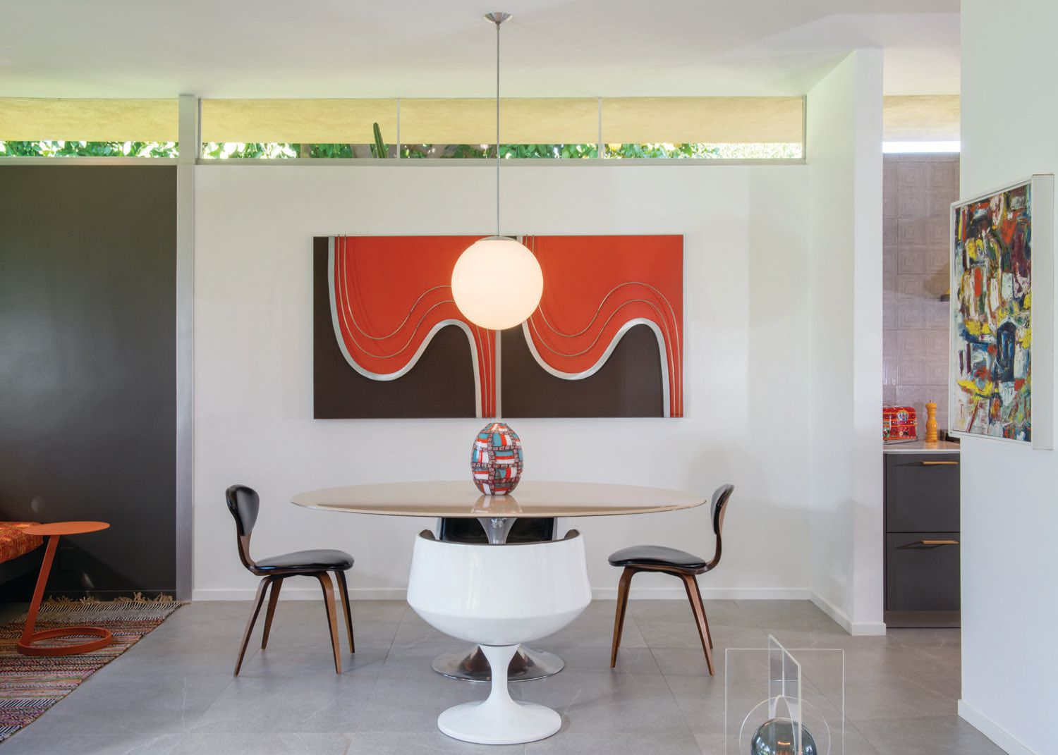 A Burke tulip dining table base—topped with a custom resin oval top by Ulloo 42—is surrounded by vintage chairs. The pendant and Curtis Jeré wall sculptures are also vintage PHOTOGRAPHED BY DAN CHAVKIN