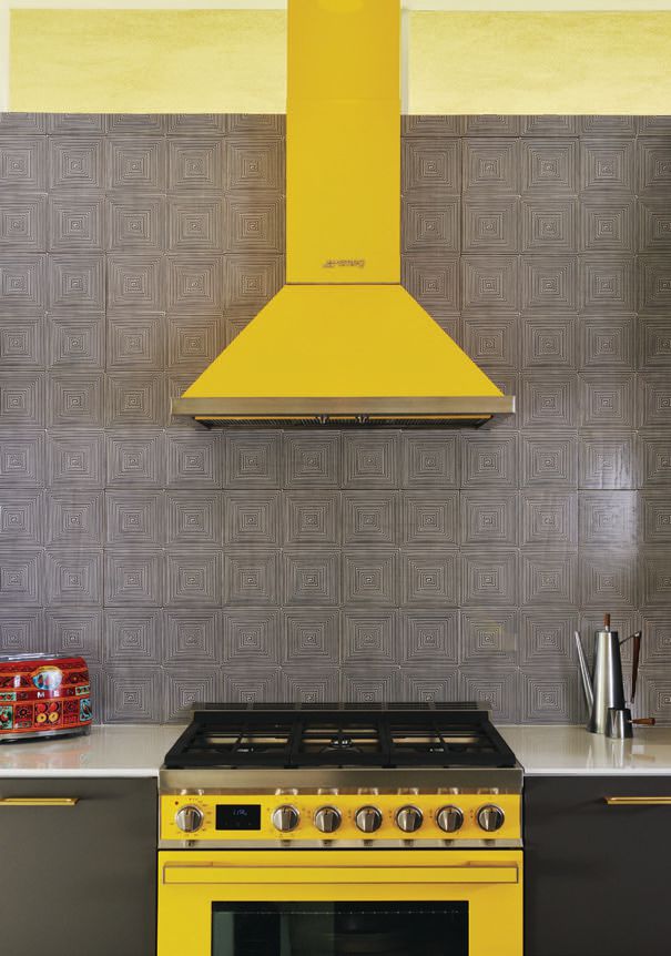 In the kitchen, a yellow range and hood by Smeg stand out against wooden backsplash tile by Mirth Studio. PHOTOGRAPHED BY DAN CHAVKIN